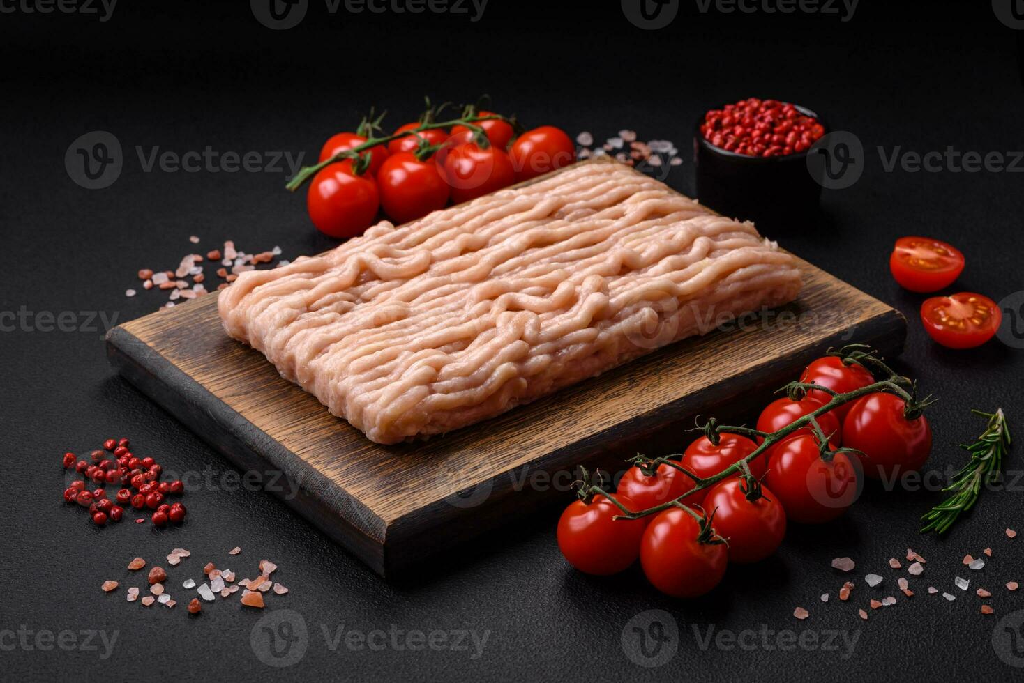 Fresh minced chicken with salt, spices and herbs on a wooden cutting board photo