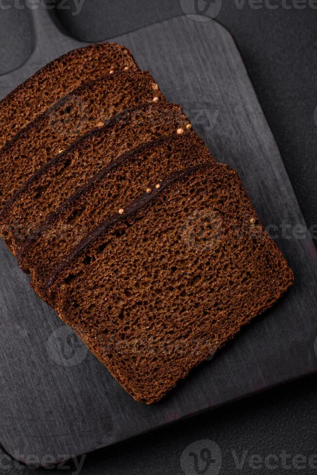 Delicious fresh brown bread with grains and seeds sliced on a wooden cutting board photo