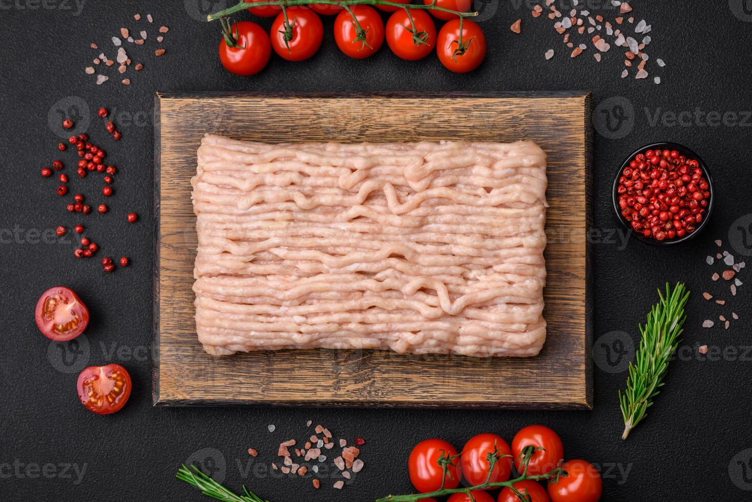 Fresh minced chicken with salt, spices and herbs on a wooden cutting board photo