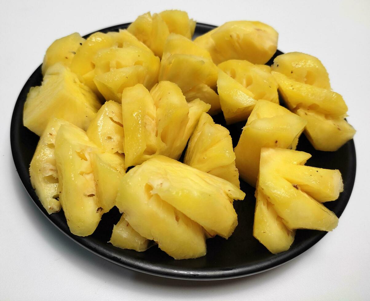 pineapple slices on black plate isolated on white background photo