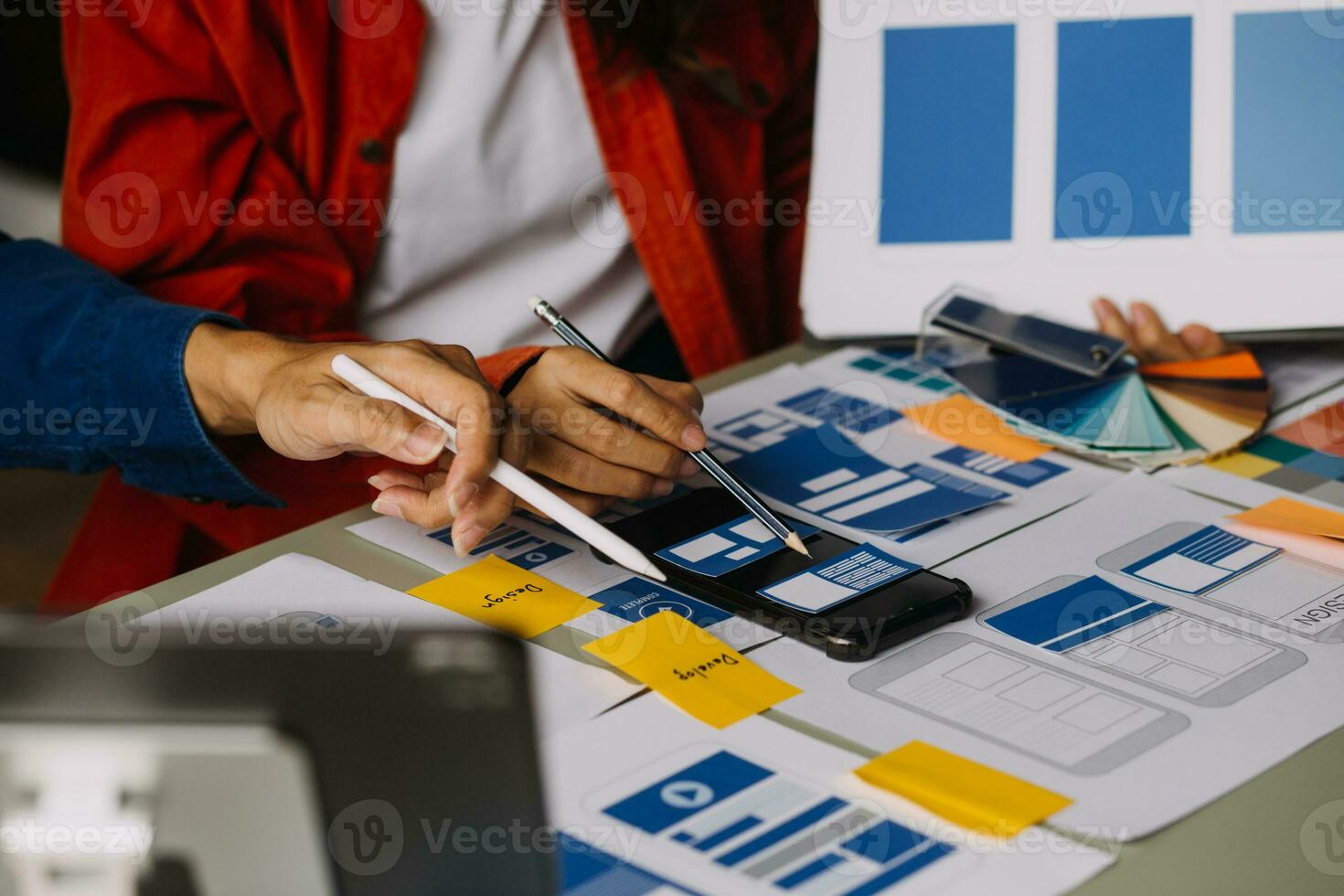 Close up ux developer and ui designer brainstorming about mobile app interface wireframe design on table with customer breif and color code at modern office.Creative digital development agency photo