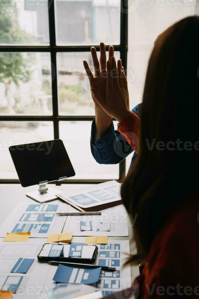 Close up ux developer and ui designer brainstorming about mobile app interface wireframe design on table with customer breif and color code at modern office.Creative digital development agency photo