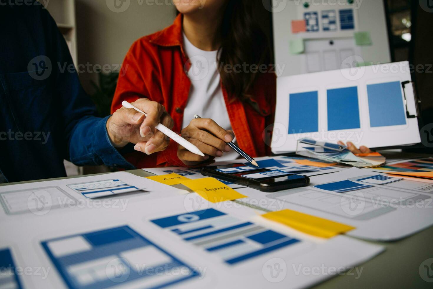 Close up ux developer and ui designer brainstorming about mobile app interface wireframe design on table with customer breif and color code at modern office.Creative digital development agency photo