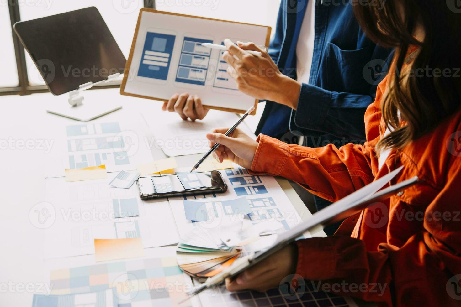 Close up ux developer and ui designer brainstorming about mobile app interface wireframe design on table with customer breif and color code at modern office.Creative digital development agency photo