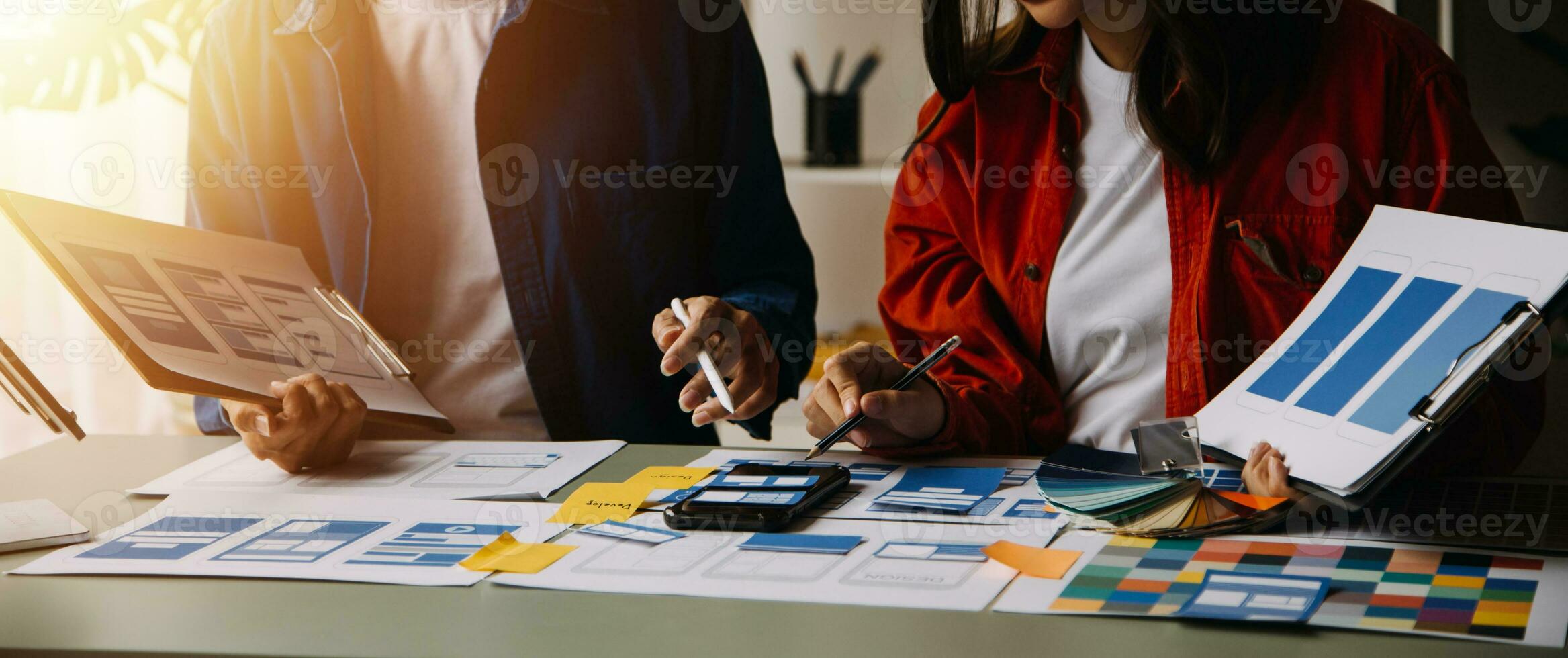 Close up ux developer and ui designer brainstorming about mobile app interface wireframe design on table with customer breif and color code at modern office.Creative digital development agency photo
