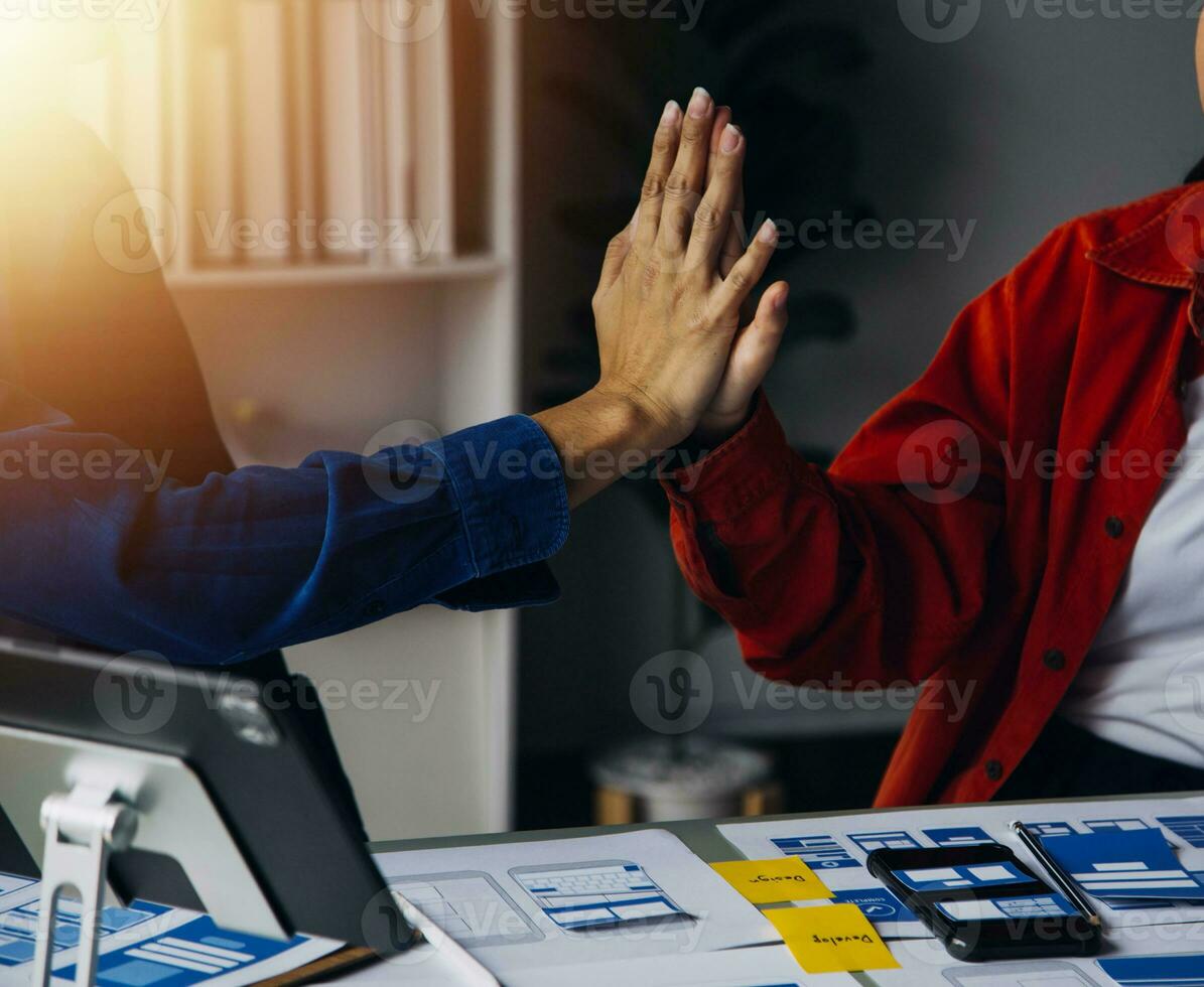 Close up ux developer and ui designer brainstorming about mobile app interface wireframe design on table with customer breif and color code at modern office.Creative digital development agency photo