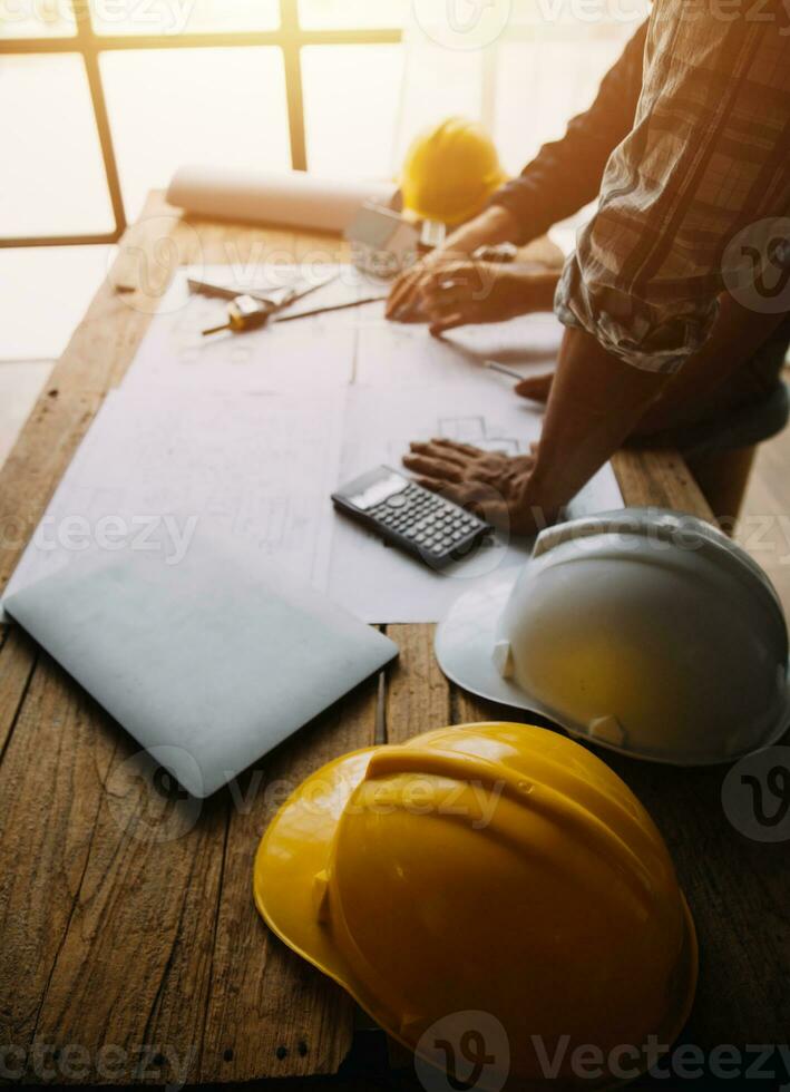 Two Specialists Inspect Commercial, Industrial Building Construction Site. Real Estate Project with Civil Engineer, Investor Use Laptop. In the Background Crane, Skyscraper Concrete Formwork Frames photo