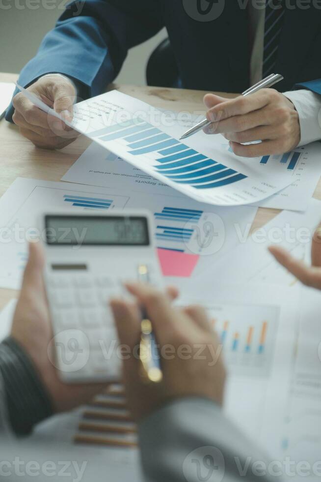 Group of confident business people point to graphs and charts to analyze market data, balance sheet, account, net profit to plan new sales strategies to increase production capacity. photo
