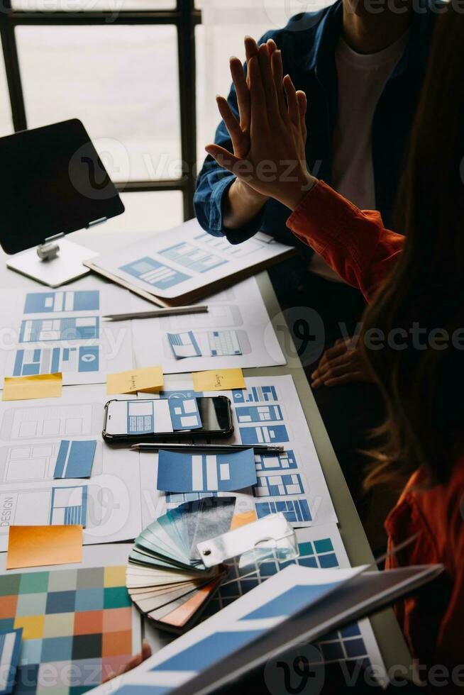 Close up ux developer and ui designer brainstorming about mobile app interface wireframe design on table with customer breif and color code at modern office.Creative digital development agency photo