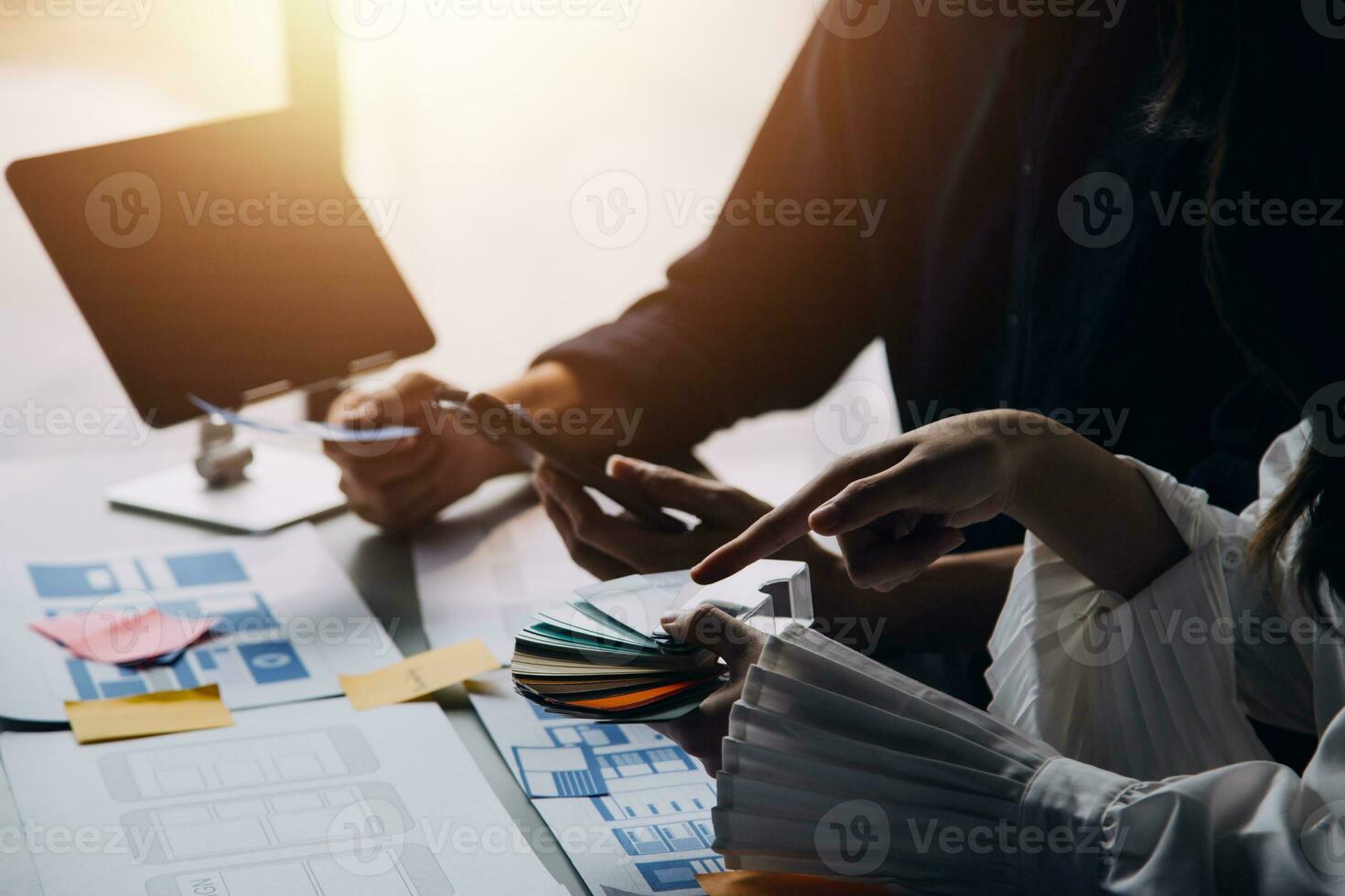Close up ux developer and ui designer brainstorming about mobile app interface wireframe design on table with customer breif and color code at modern office.Creative digital development agency photo