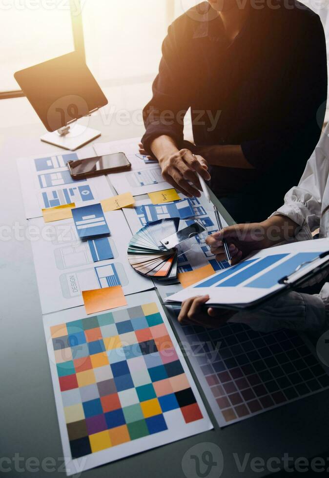 Close up ux developer and ui designer brainstorming about mobile app interface wireframe design on table with customer breif and color code at modern office.Creative digital development agency photo