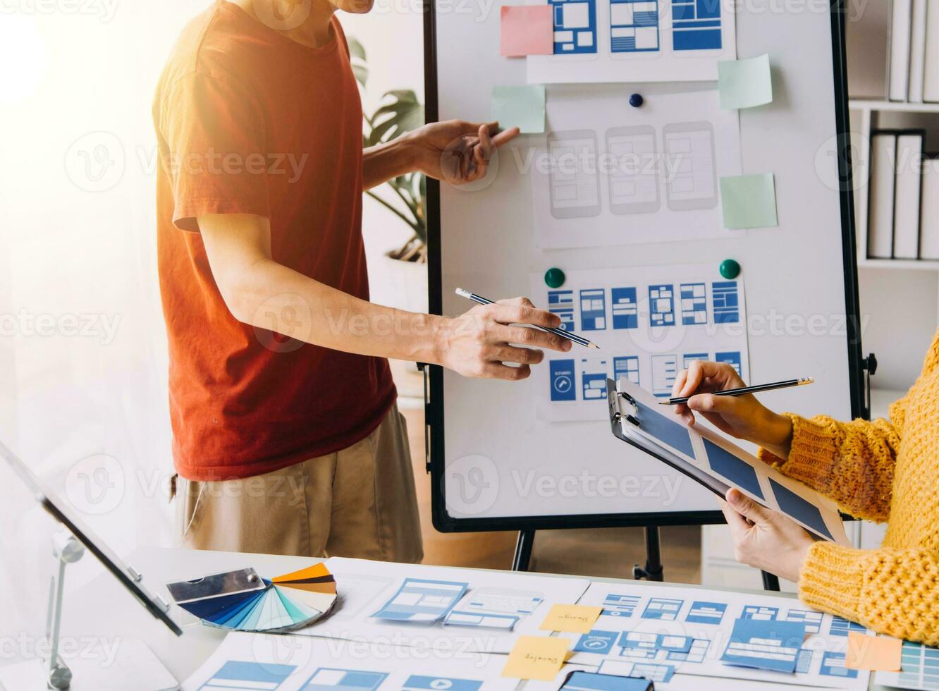 Close up ux developer and ui designer brainstorming about mobile app interface wireframe design on table with customer breif and color code at modern office.Creative digital development agency photo
