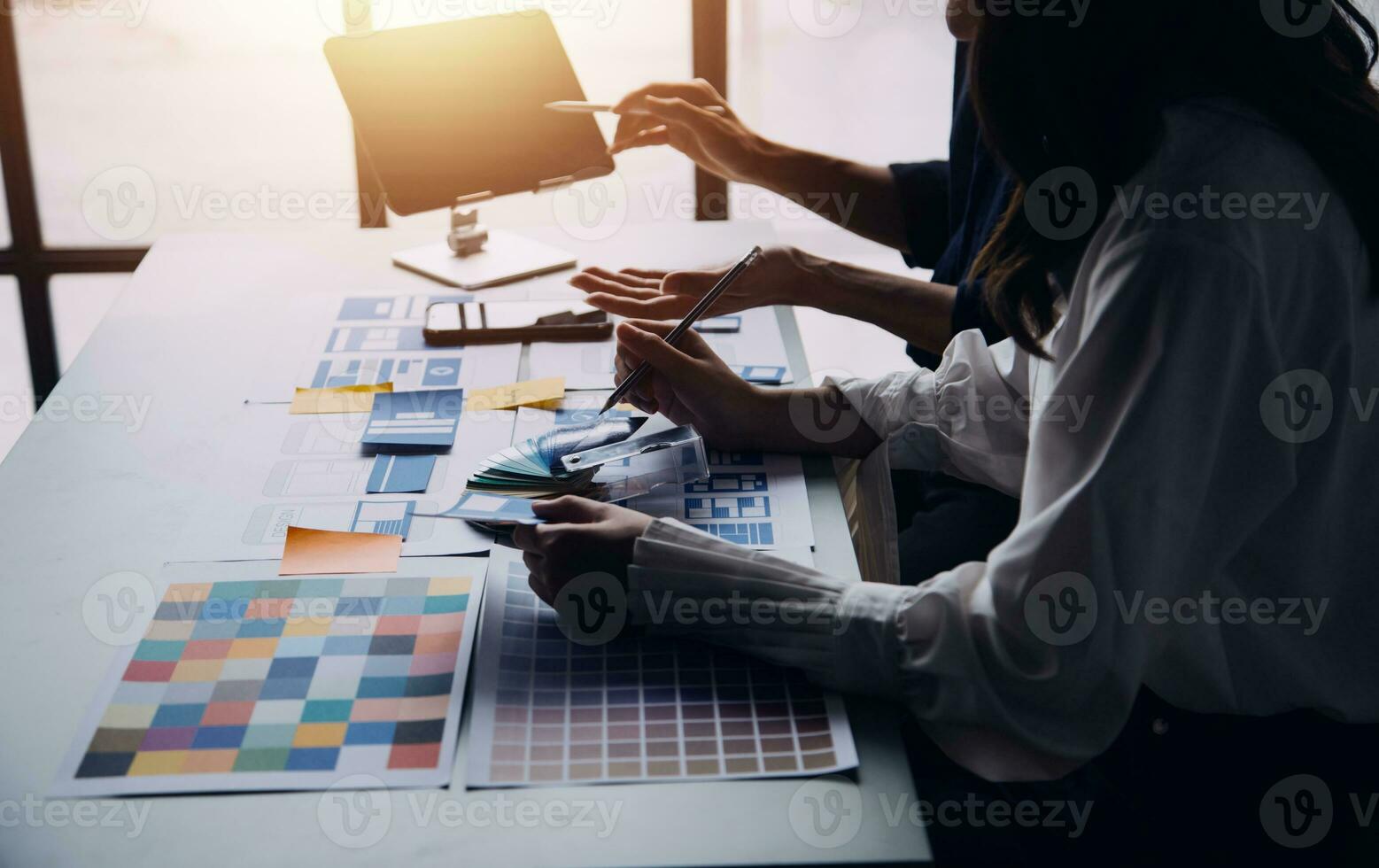 Close up ux developer and ui designer brainstorming about mobile app interface wireframe design on table with customer breif and color code at modern office.Creative digital development agency photo