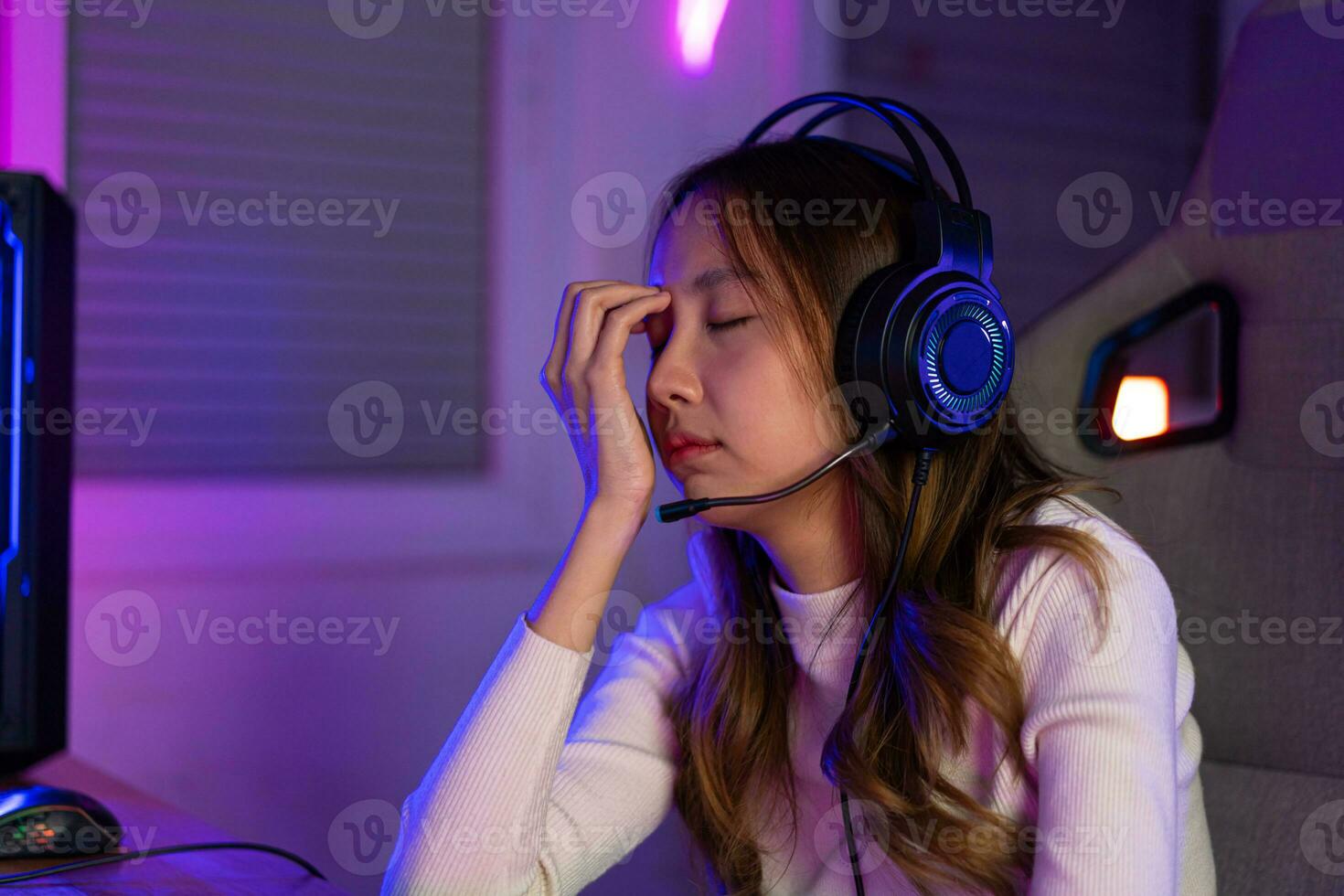 ojos cansado. jugador y e-sport en línea de asiático mujer jugando en línea computadora vídeo juego con Encendiendo efecto foto
