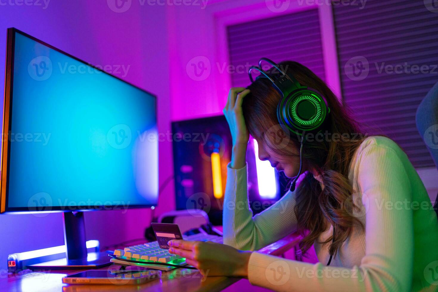 Top up online game with credit card concept. Gamer and E-Sport online of Asian woman playing online computer video game with lighting effect, broadcast streaming live at home. Gamer and E-Sport gaming photo