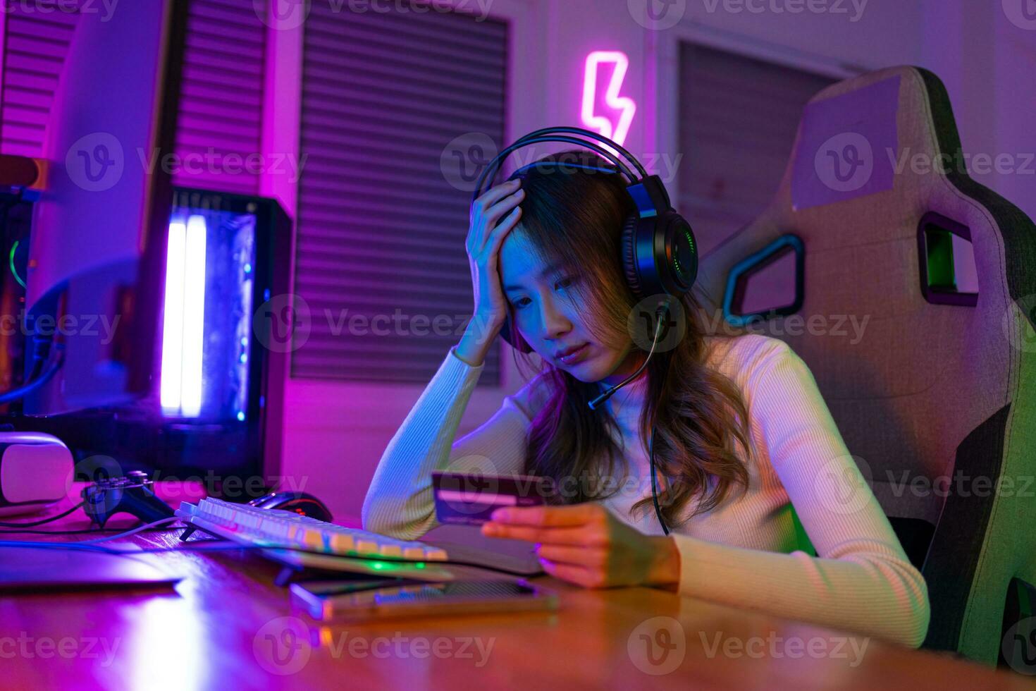 Top up online game with credit card concept. Gamer and E-Sport online of Asian woman playing online computer video game with lighting effect, broadcast streaming live at home. Gamer and E-Sport gaming photo