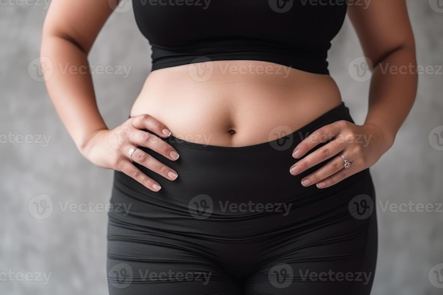overweight woman in sportswear with mild obesity holding her stomach photo