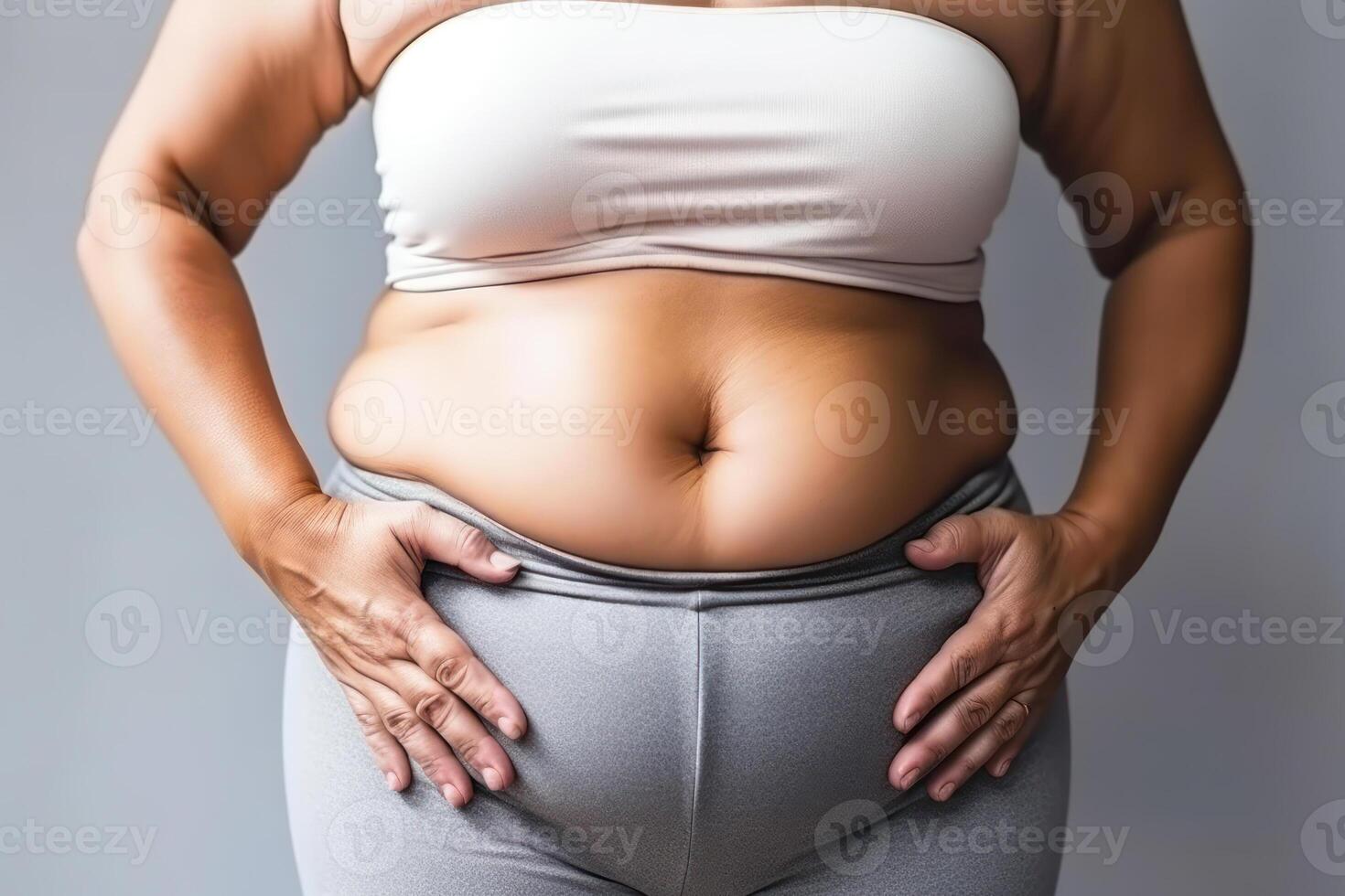 overweight woman in sportswear with mild obesity holding her stomach photo