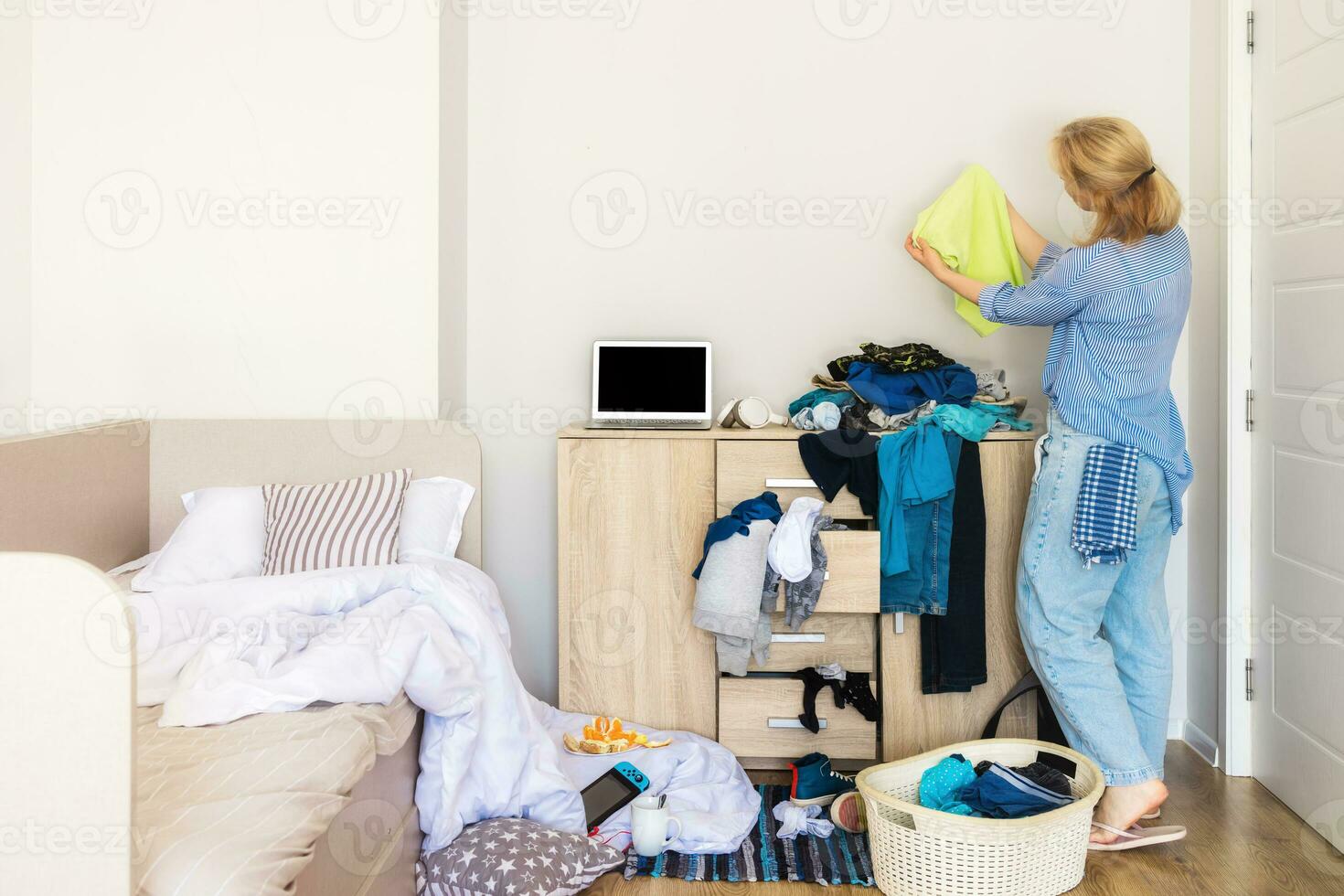 woman entered her child's room with a mess to collect dirty things and clean up photo