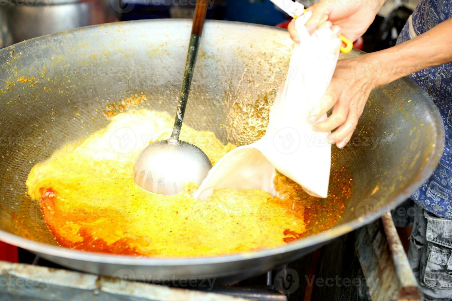 cooking food Pour the coconut milk into the golden orange curry in the pan . photo