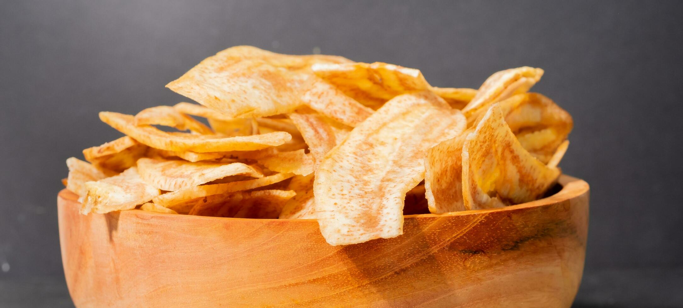 Banana chips with a sweet and salty taste made from fried raw bananas in a wooden bowl. Traditional snacks photo