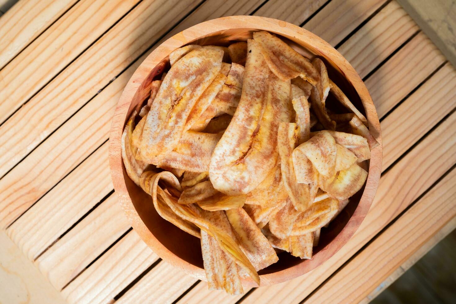 Banana chips with a sweet and salty taste made from fried raw bananas in a wooden bowl. Traditional snacks photo