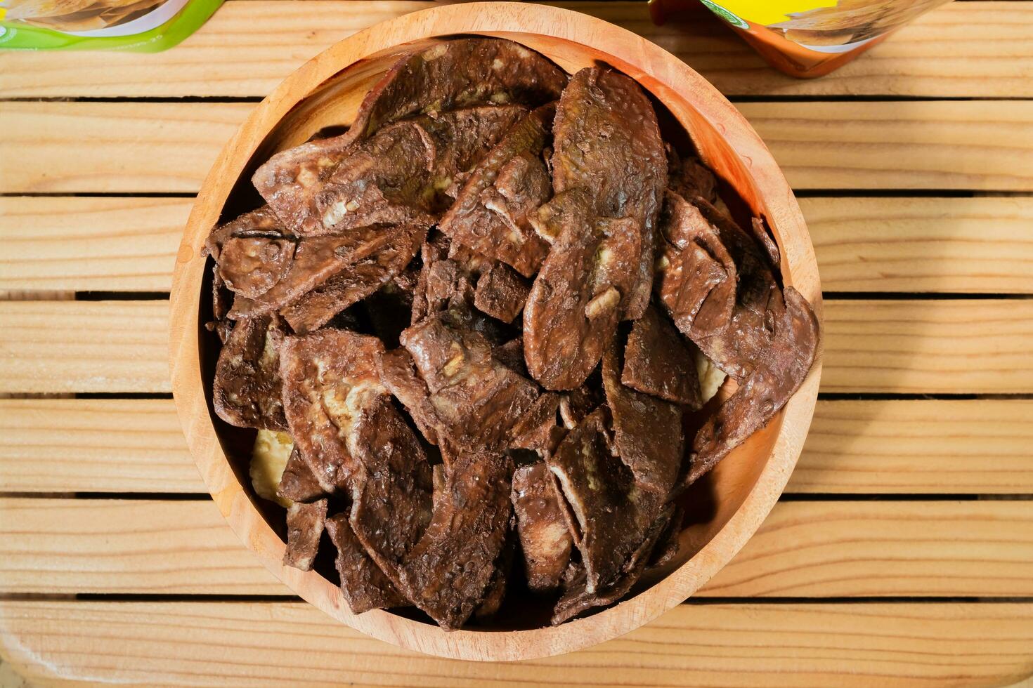 Banana chips with chocolate flavor made from raw bananas fried in a wooden bowl. Traditional snacks photo