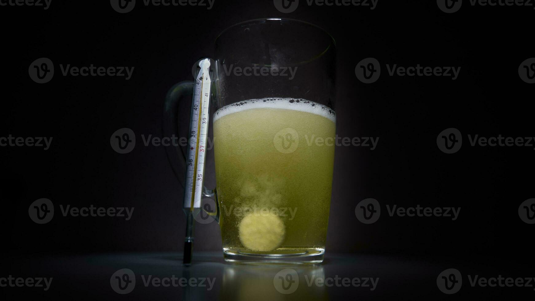 Top view of water soluble pills next to a glass thermometer showing fever symptoms photo