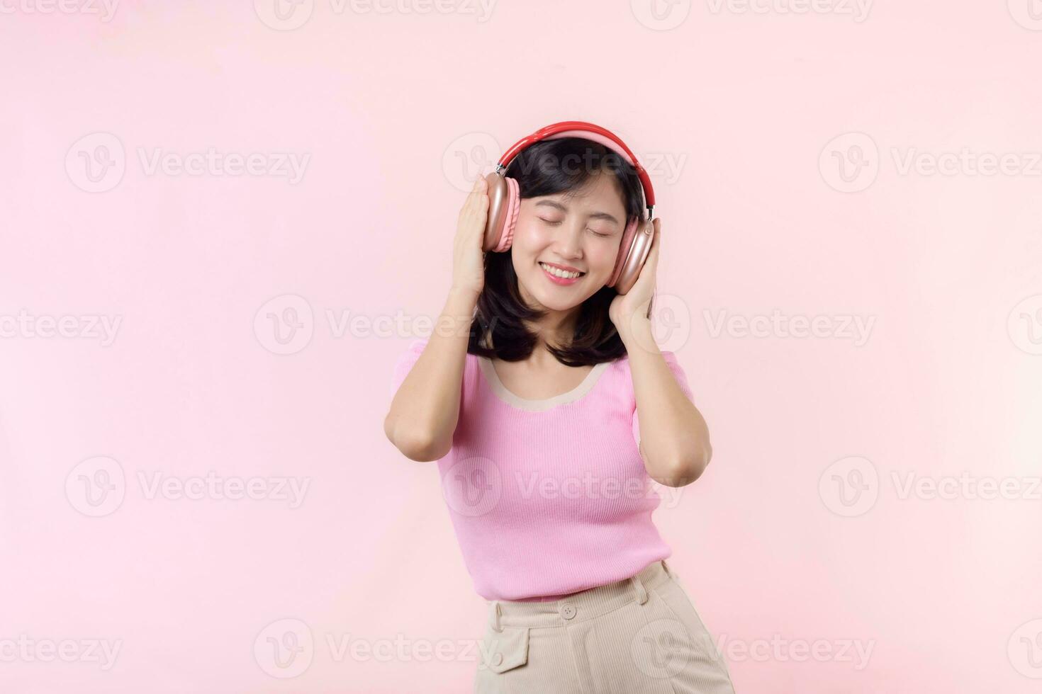 Smile pretty model person listen music song and enjoy dance with wireless headphone online audio radio sound. Positive fun exited joyful youth female woman sing on pink isolated background studio photo