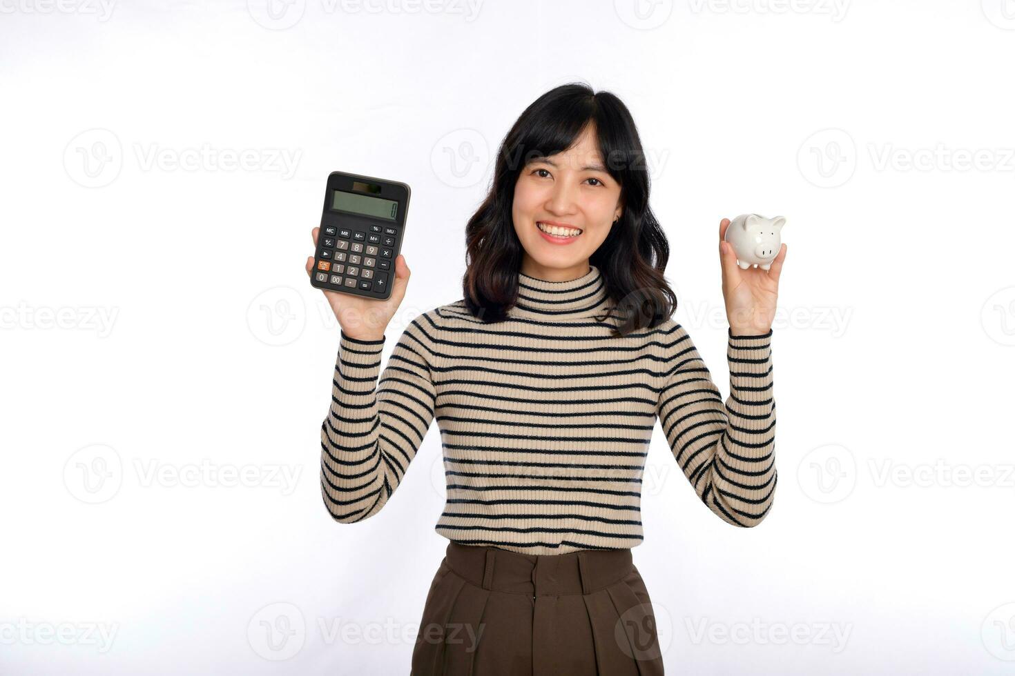 Portrait of young Asian woman casual uniform holding white piggy bank and calculator isolated on white background, Financial and bank saving money concept photo