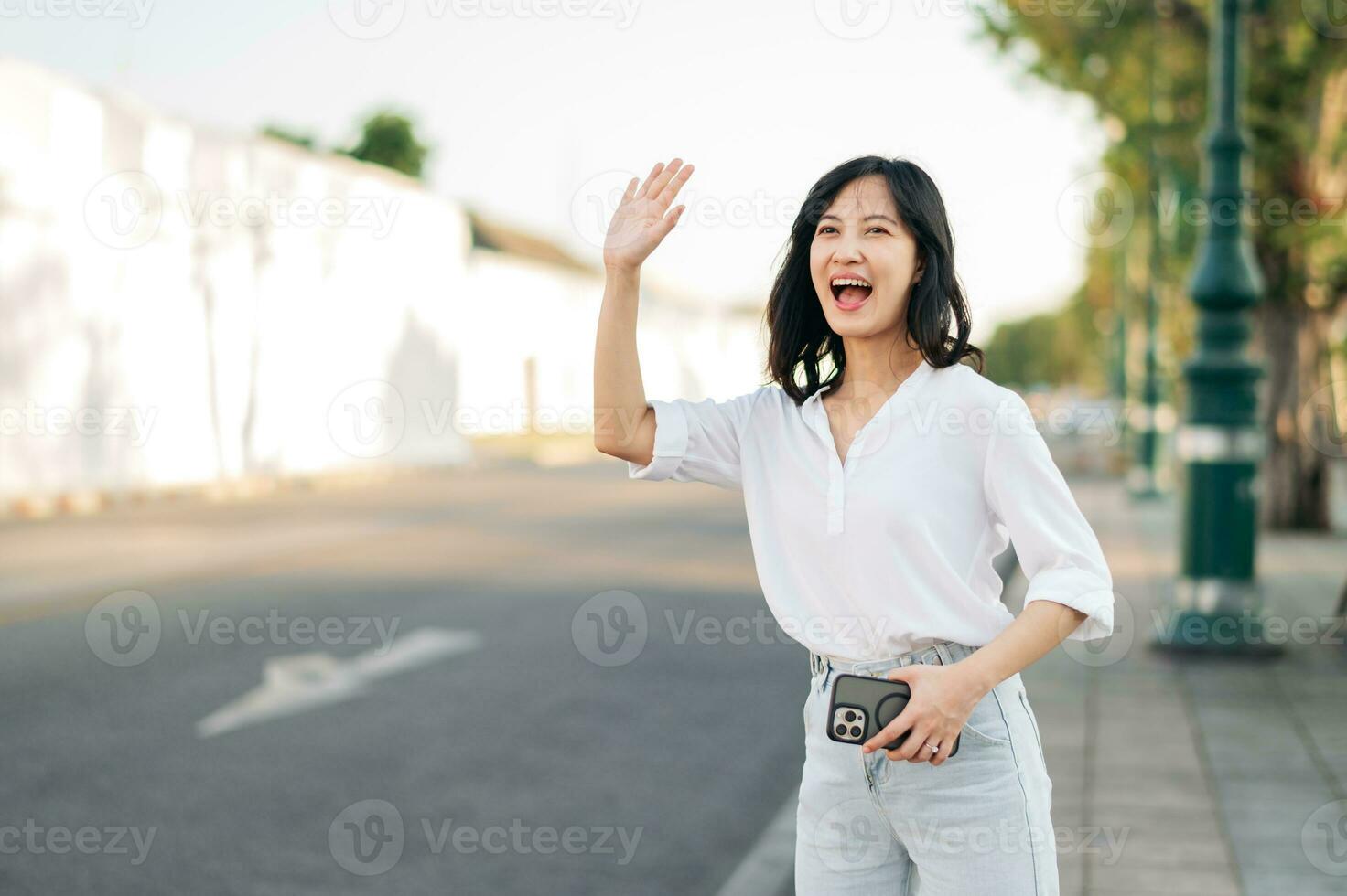 Portrait young beautiful asian woman waving hand to friend by the street in sunny holiday. photo