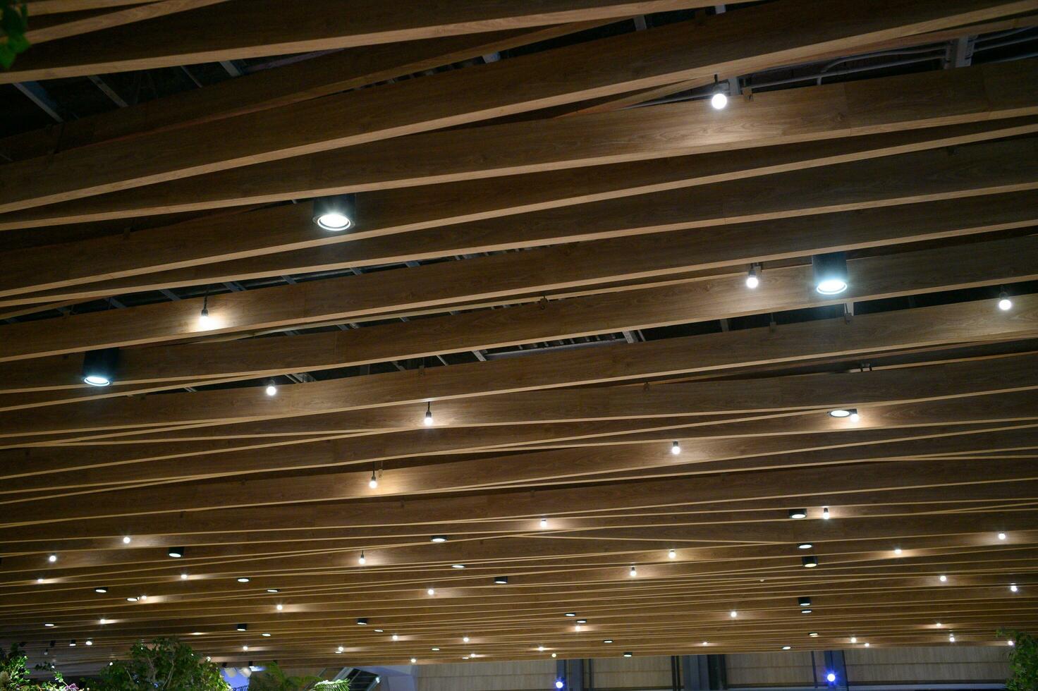 Light ceiling with wood interior design. Wooden ceiling decor lamp in room, home indoor. Modern style material with plank, timber architecture in brown colour with electricity bulb for meeting hall. photo