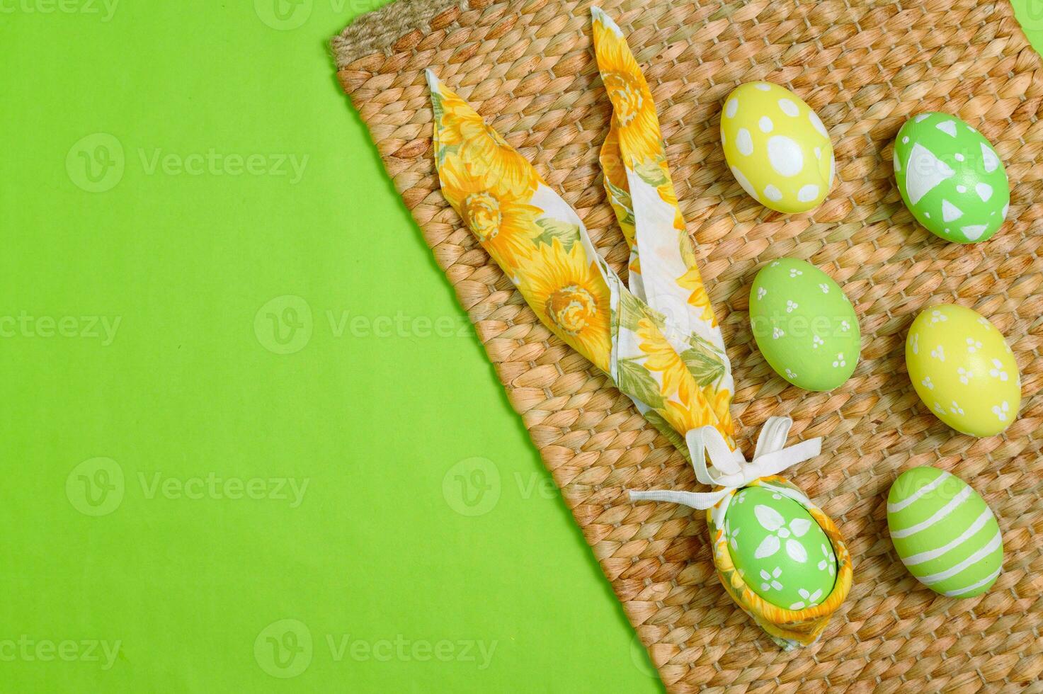 Happy Easter holiday greeting card design concept. Colorful Easter Eggs and spring flowers on pastel green background. Flat lay, top view, copy space. photo