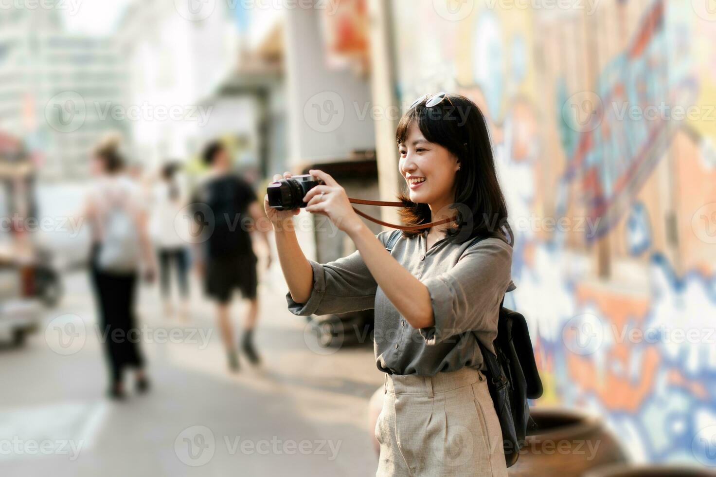 Young Asian woman backpack traveler using digital compact camera, enjoying street cultural local place and smile. Traveler checking out side streets. photo
