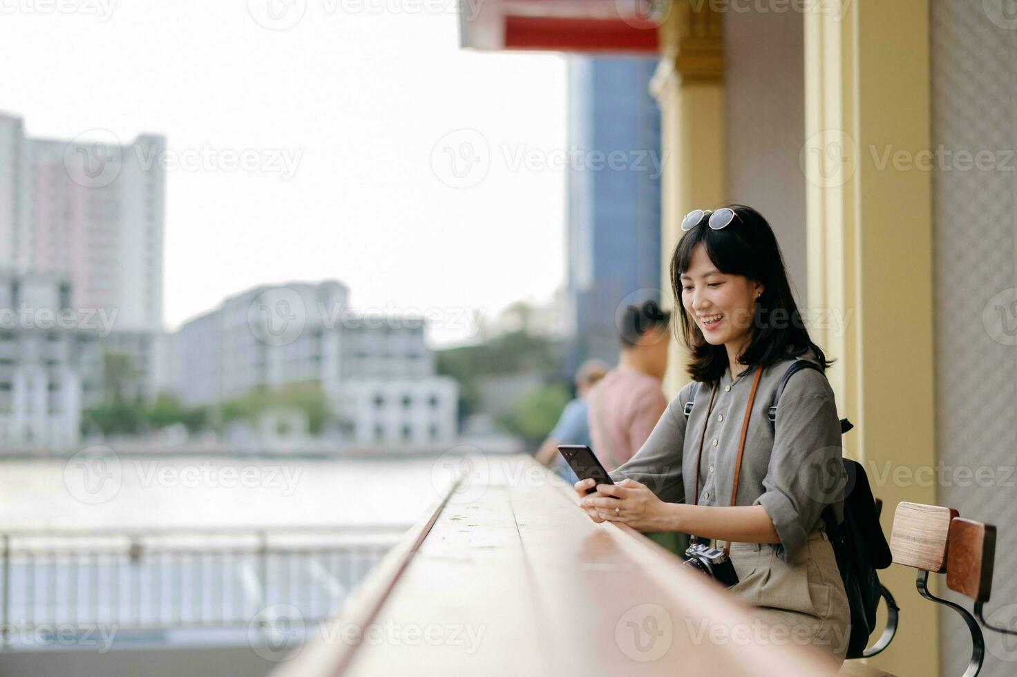 Young Asian woman backpack traveler using mobile phone in express boat pier on Chao Phraya River in Bangkok. photo