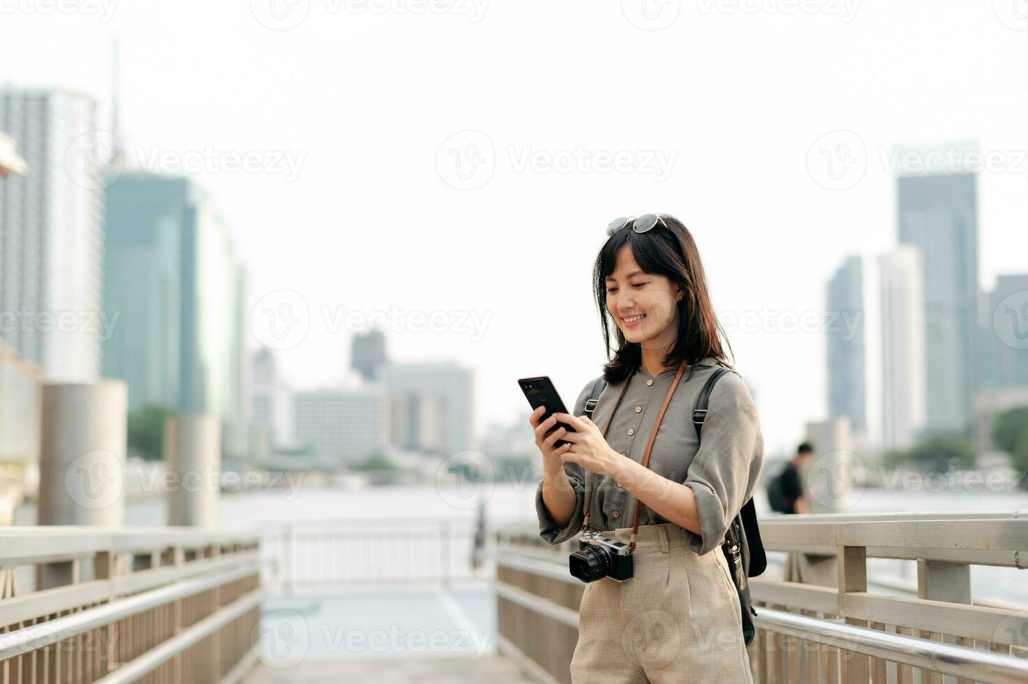 Young Asian woman backpack traveler using mobile phone in express boat pier on Chao Phraya River in Bangkok. photo