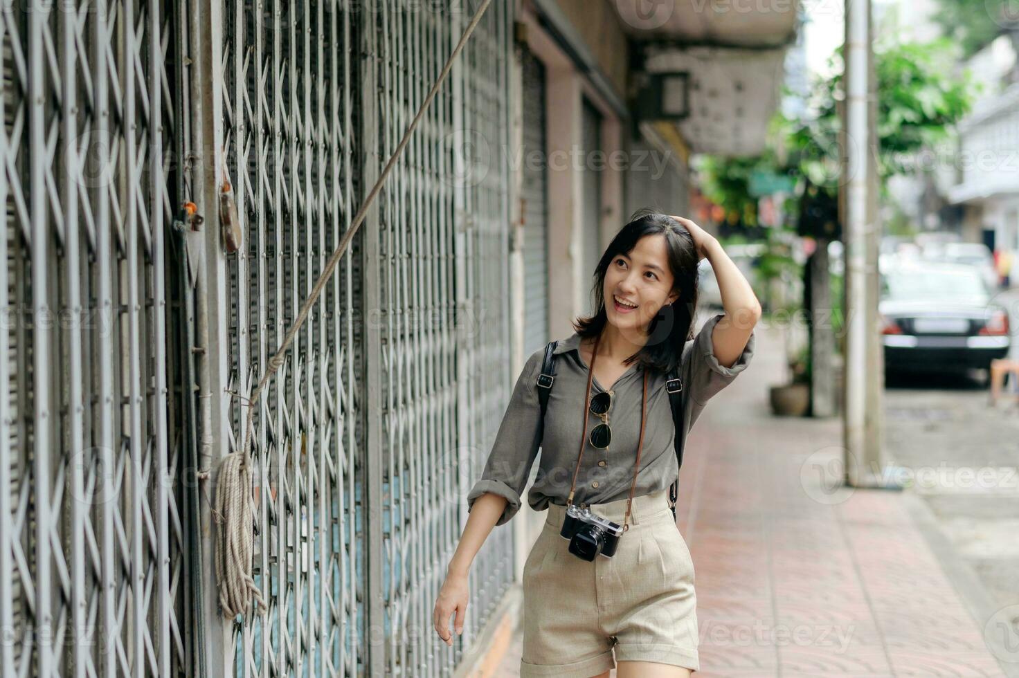 Young Asian woman backpack traveler enjoying street cultural local place and smile. Traveler checking out side streets. photo