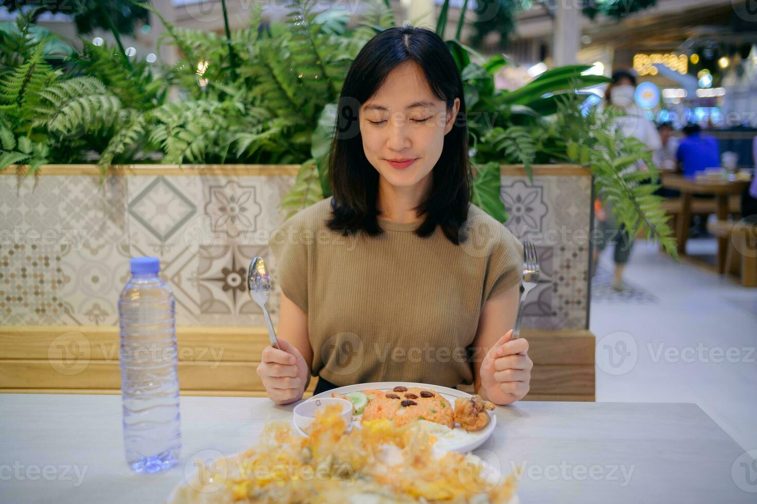 Smiling young Asian woman enjoying meal such as American fried rice and fried clams in a restaurant. photo