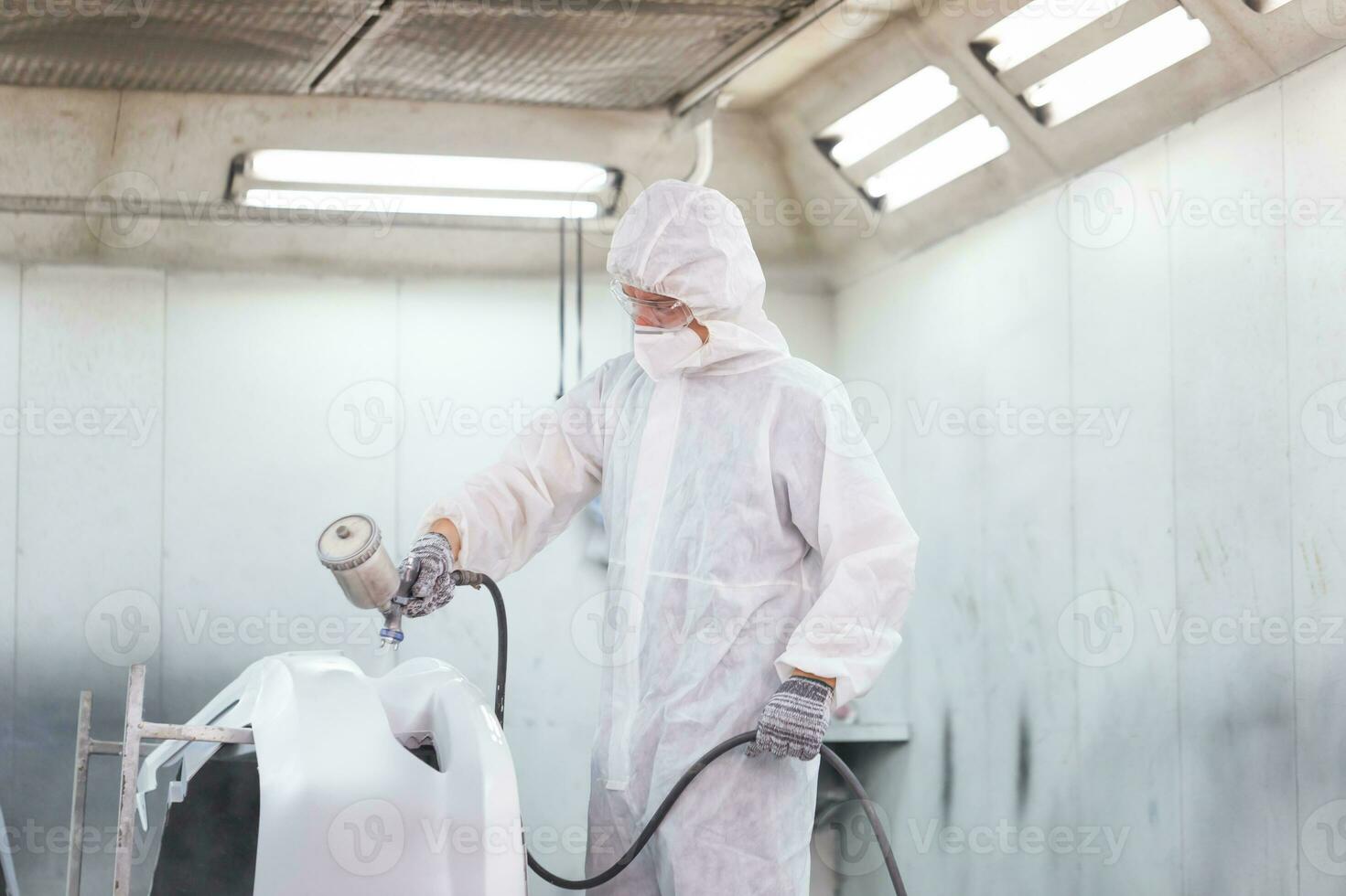 Mechanic painting car in chamber. Worker using spray gun and airbrush and painting a car, Garage painting car service repair and maintenance photo