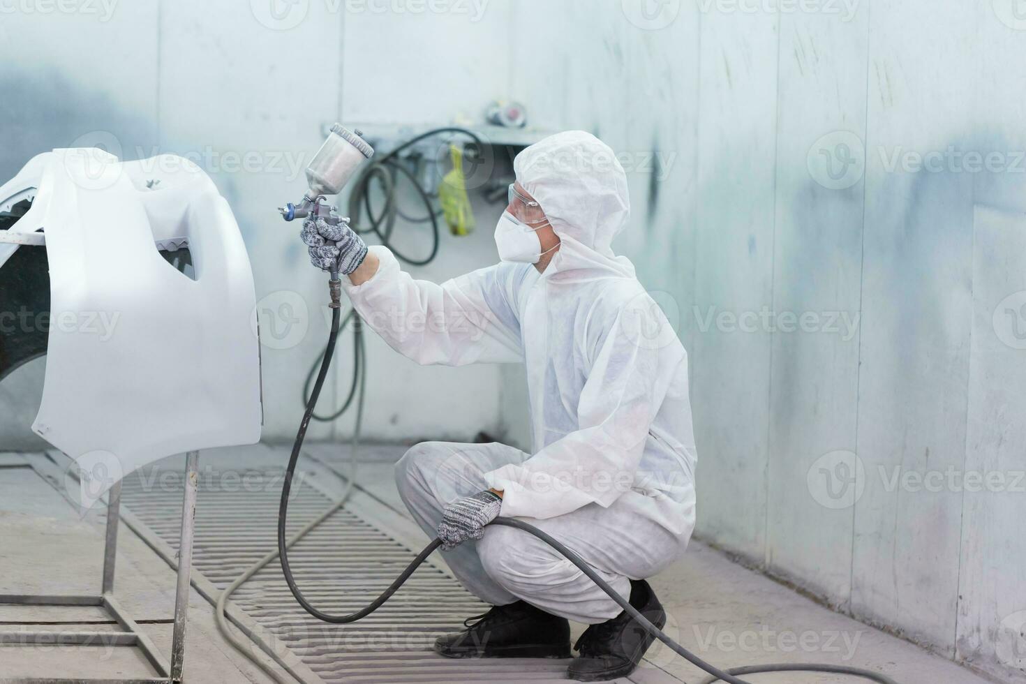 Mechanic painting car in chamber. Worker using spray gun and airbrush and painting a car, Garage painting car service repair and maintenance photo