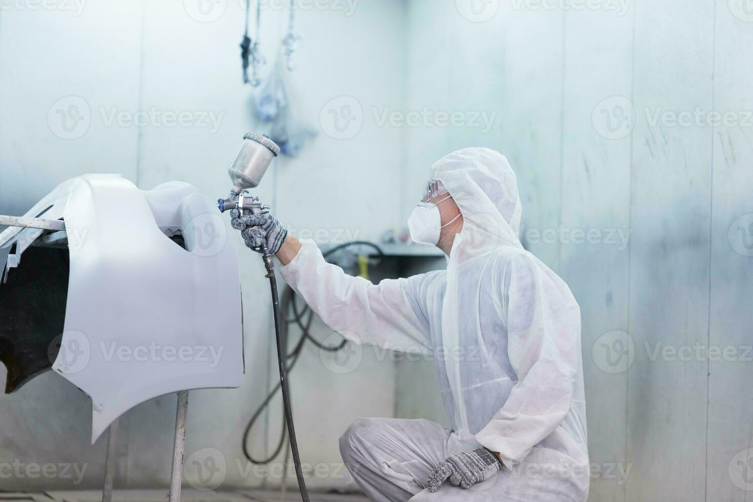 Mechanic painting car in chamber. Worker using spray gun and airbrush and painting a car, Garage painting car service repair and maintenance photo