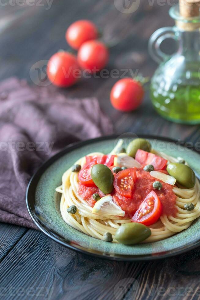 pasta con tomate salsa, aceitunas y alcaparras en el plato foto