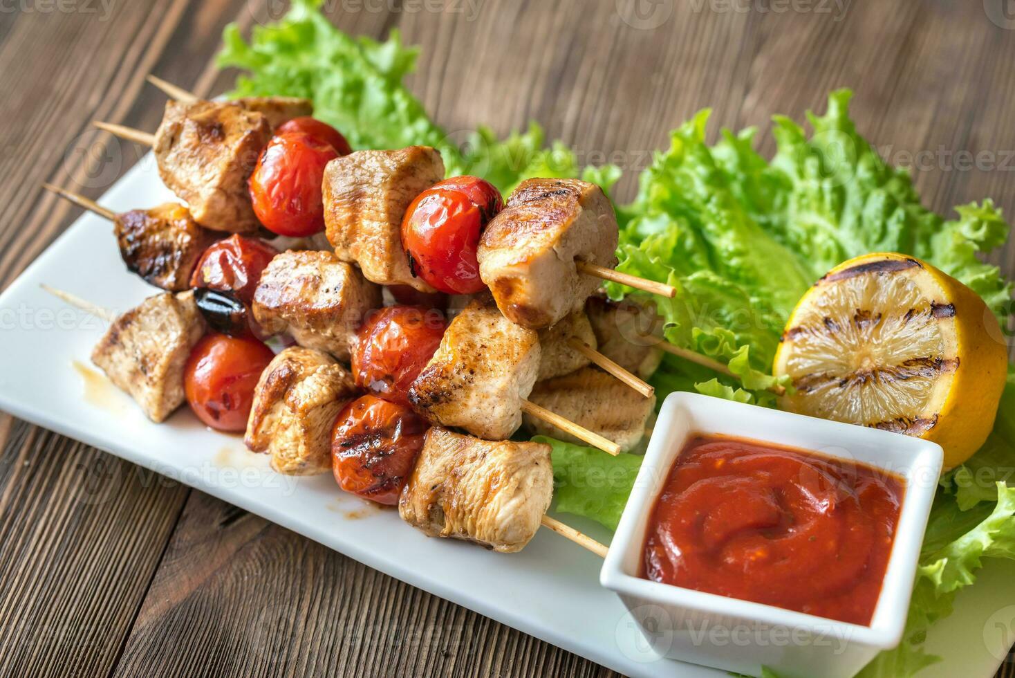 brochetas de pollo a la parrilla en el plato blanco foto