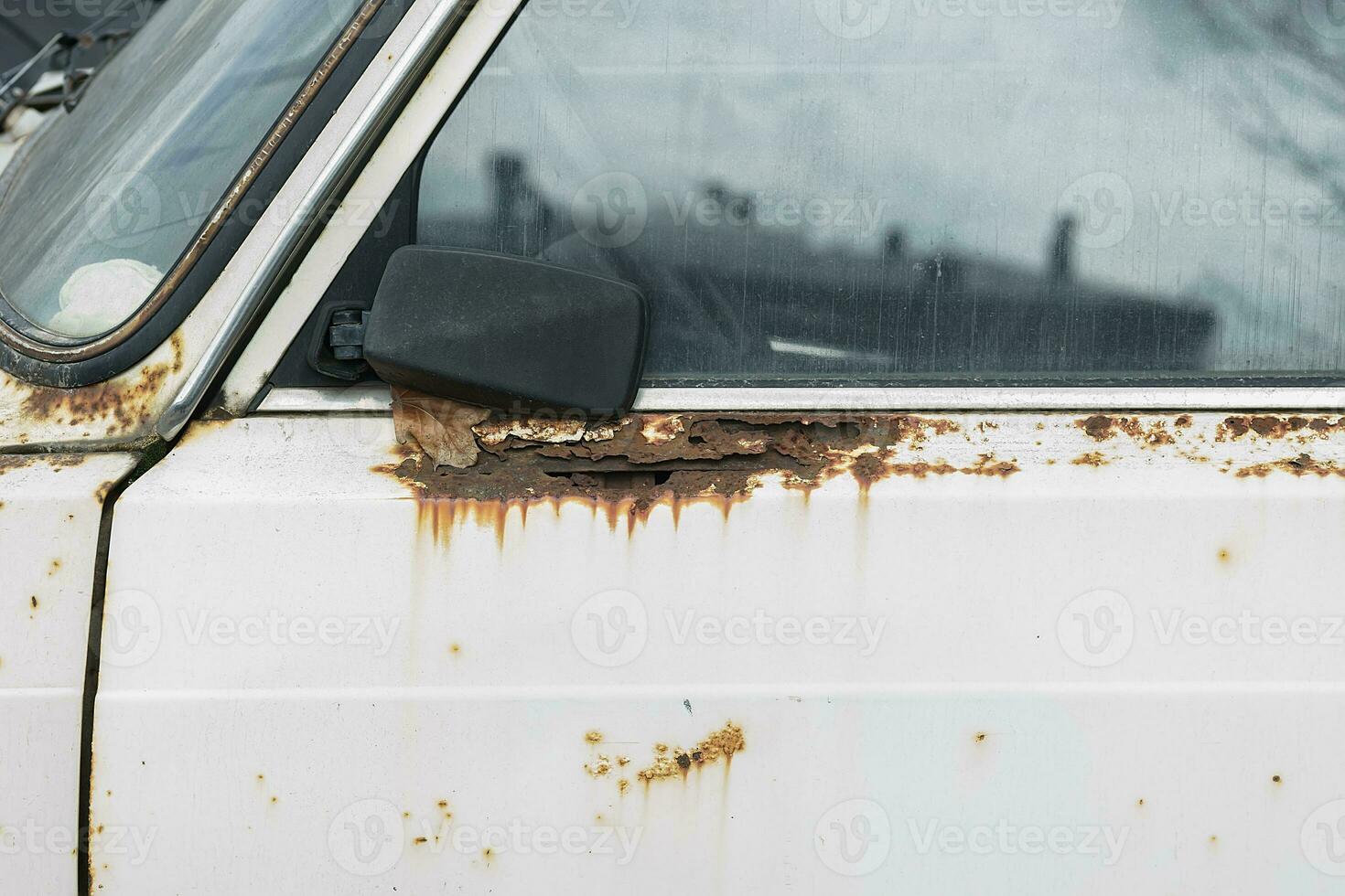 Old rusty and dusty car parked in the street. photo