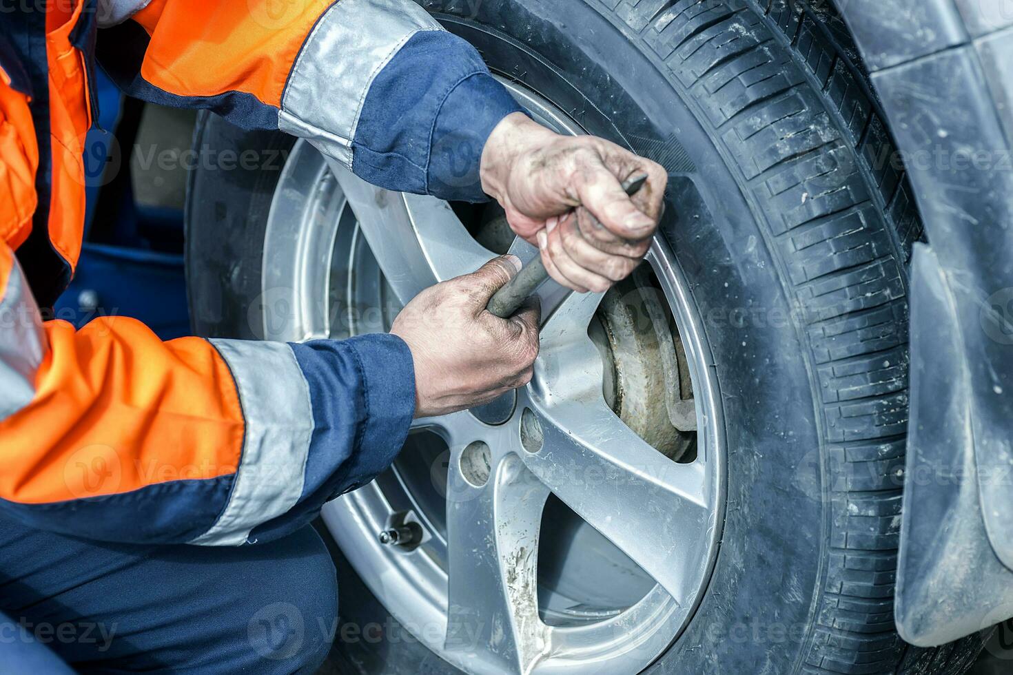 Car wheel replacement. Self-service tire fitting concept. Using a wheel wrench to twist the wheel nuts. photo