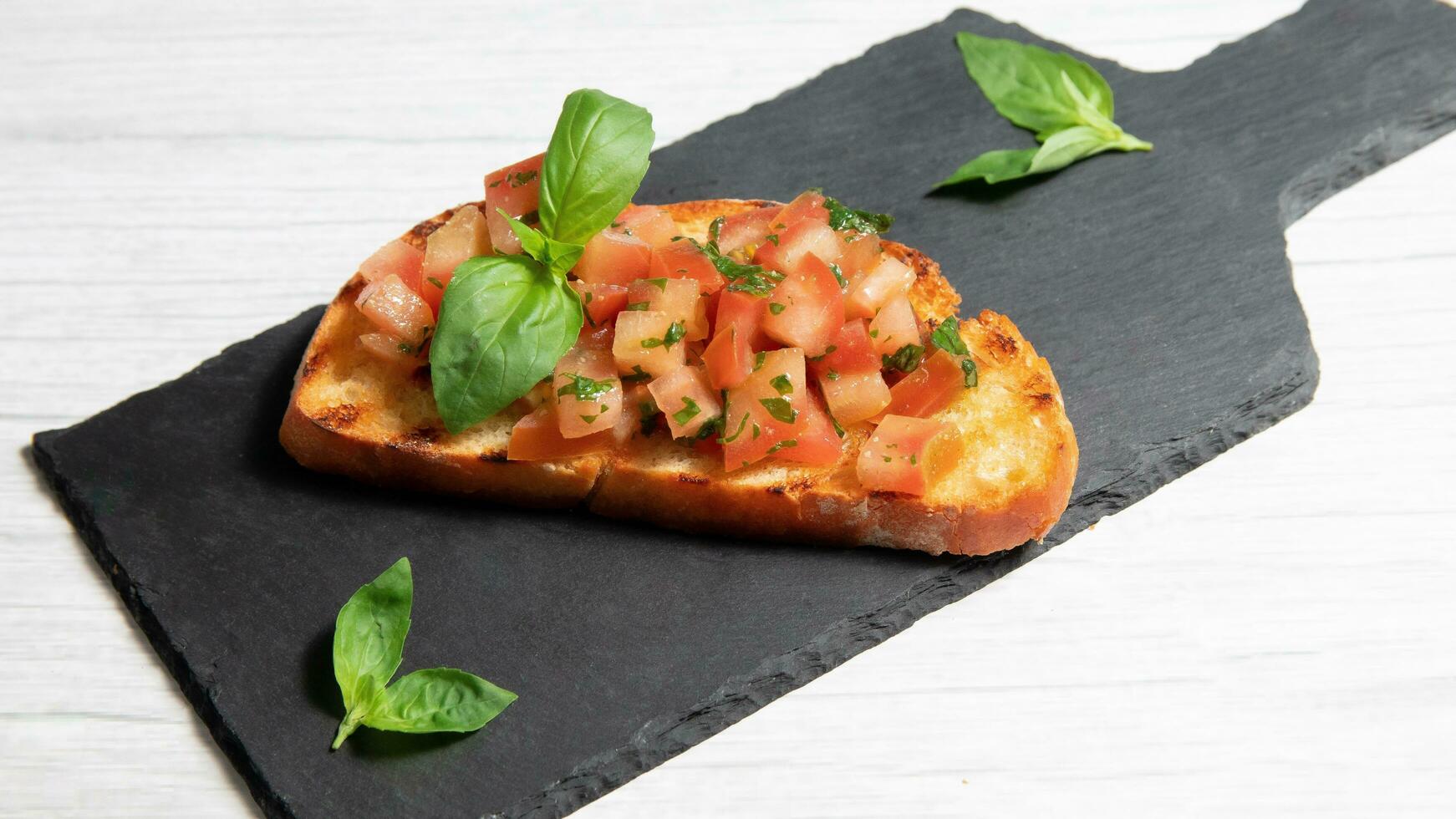 bruschetta on a black plate, on a white wooden background photo