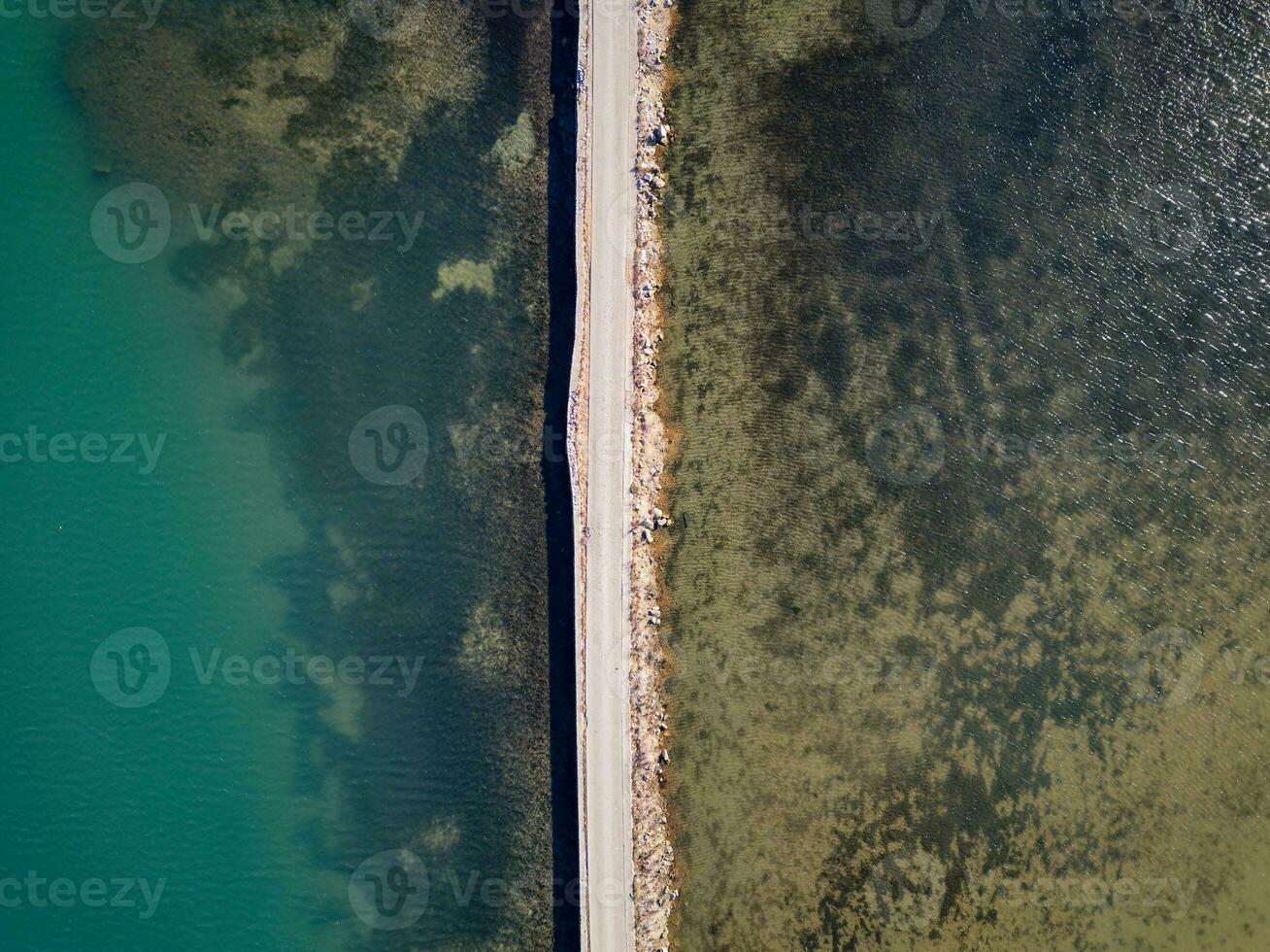 Road passing through the lake. Travel and explore concept. Road in between water. Aerial drone view. photo
