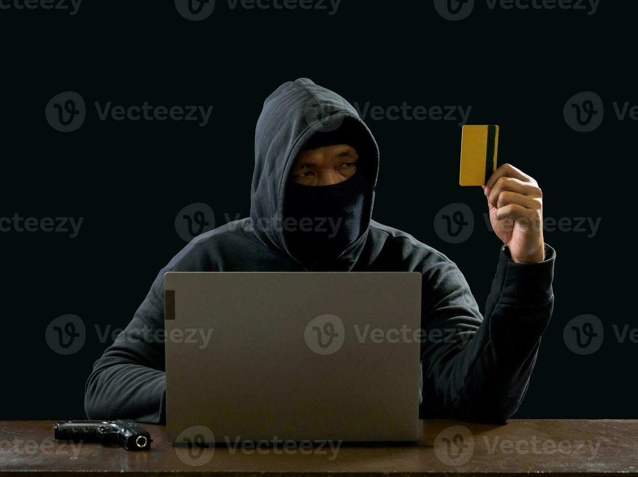 Hacker spy man one person in black hoodie sitting on a table looking computer laptop used login password attack security to circulate data digital in internet network system, night dark background. photo