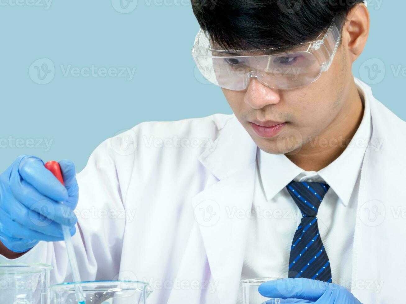 Asian man student scientist or doctor one person, wearing a white gown, standing, looking and smiling, blue background with a stethoscope auscultating the heart around his neck. photo