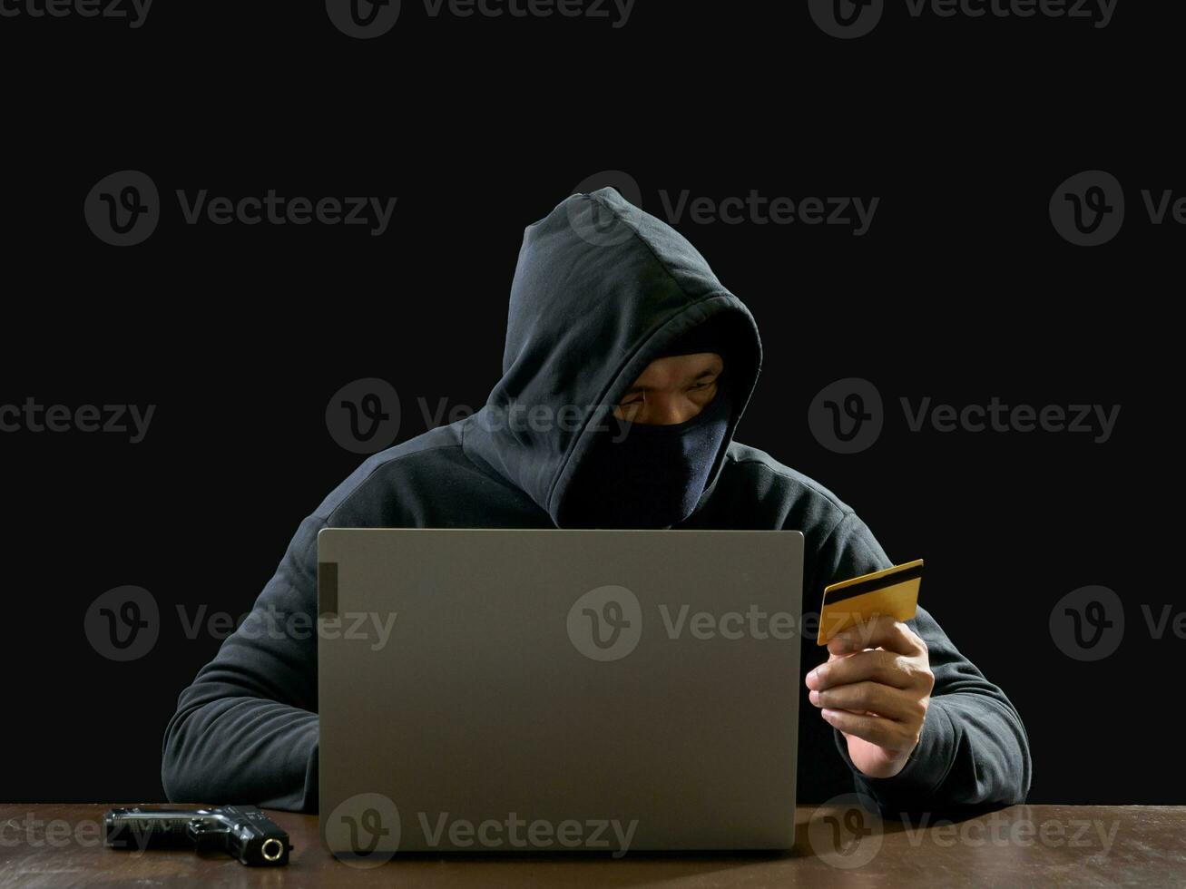 Hacker spy man one person in black hoodie sitting on a table looking computer laptop used login password attack security to circulate data digital in internet network system, night dark background. photo